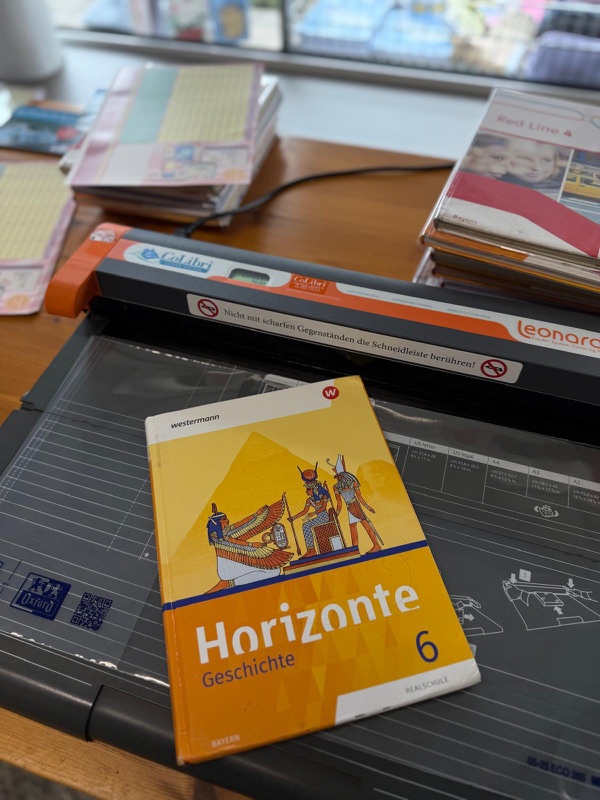 Ein Schulbuch liegt zum Einbinden auf dem CoLibrì-System im Ladengeschäft