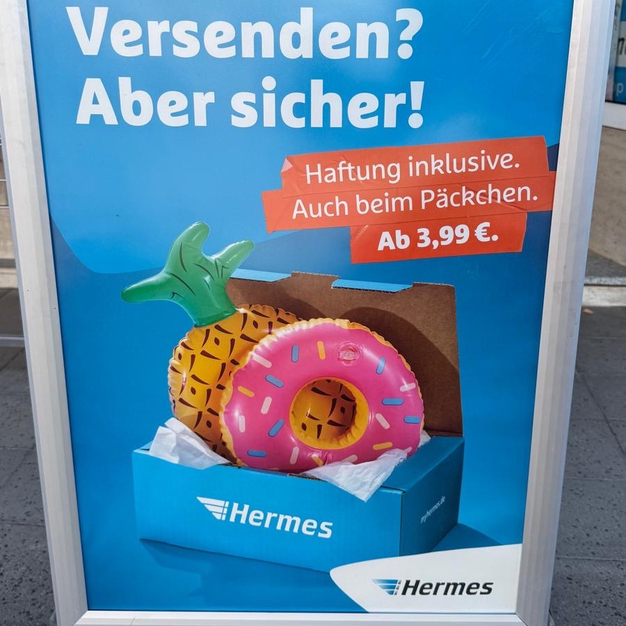 Hermes-Aufsteller vor dem Laden mit der Aufschrift „Versenden? Aber sicher!“ und dem Hermes-Logo